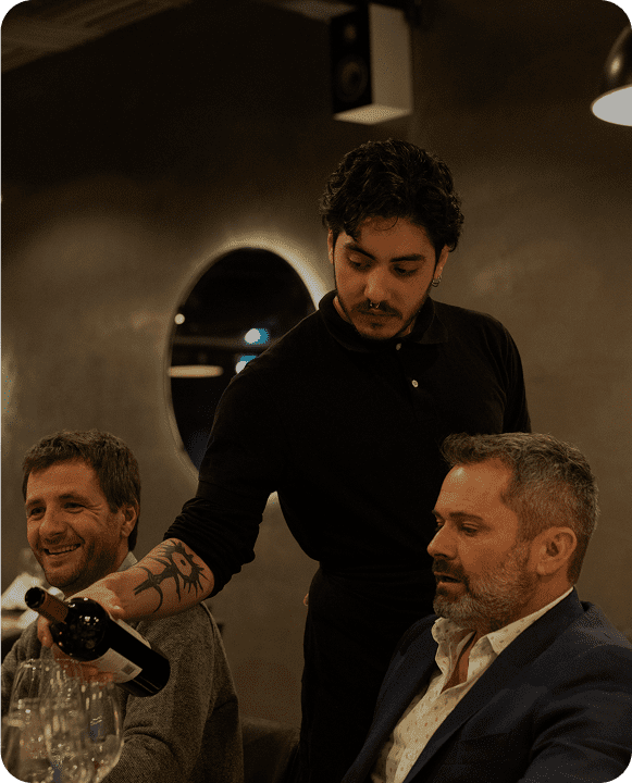 Waiter pouring wine for seated guests.