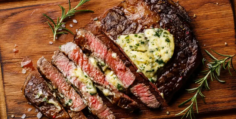 Sliced steak with herb butter and rosemary.