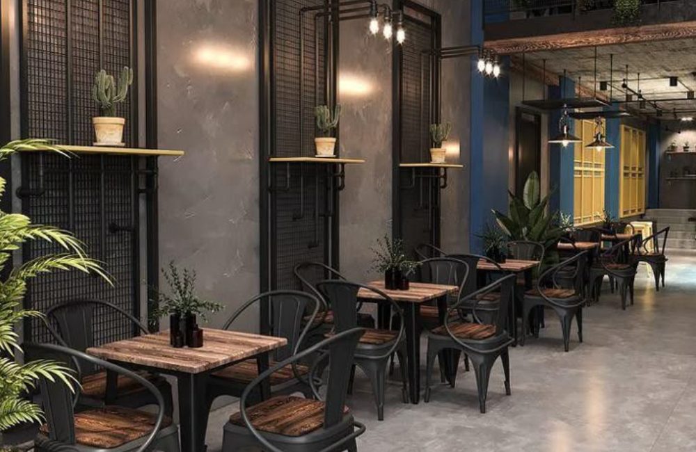 Cozy outdoor café seating with wooden tables and black chairs under soft lighting.